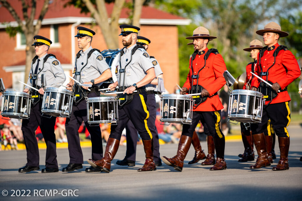 RCMP Members marching in uniform with drums in unison. 