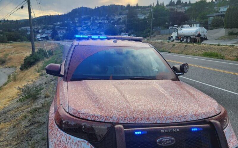 Un véhicule de police éclaboussé de produit ignifuge rouge pendant la saison des feux de forêt à Peachland (C.-B.) en 2025.